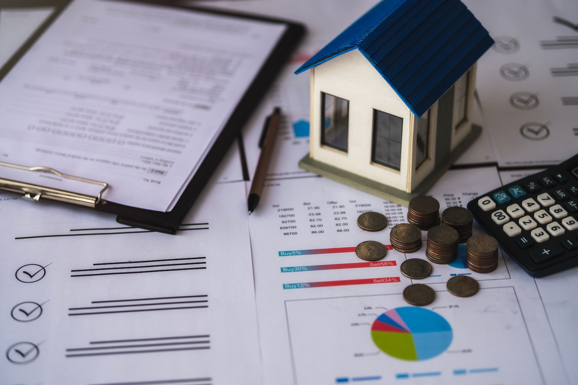 View of house model and pile of coins placed on document. Concept. Real estate business. Investment planning and property taxes Bank concept, loan, home sale and home insurance concept.