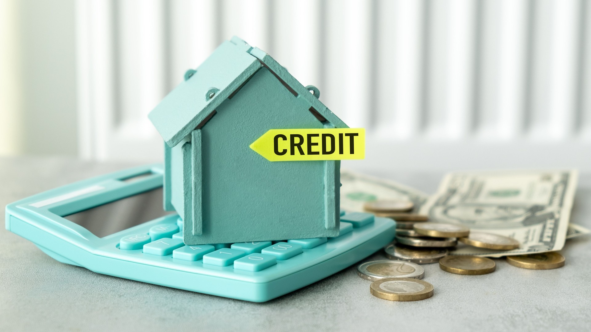 Credit text on a miniature house on a calculator with scattered money and coins, Home loan concept